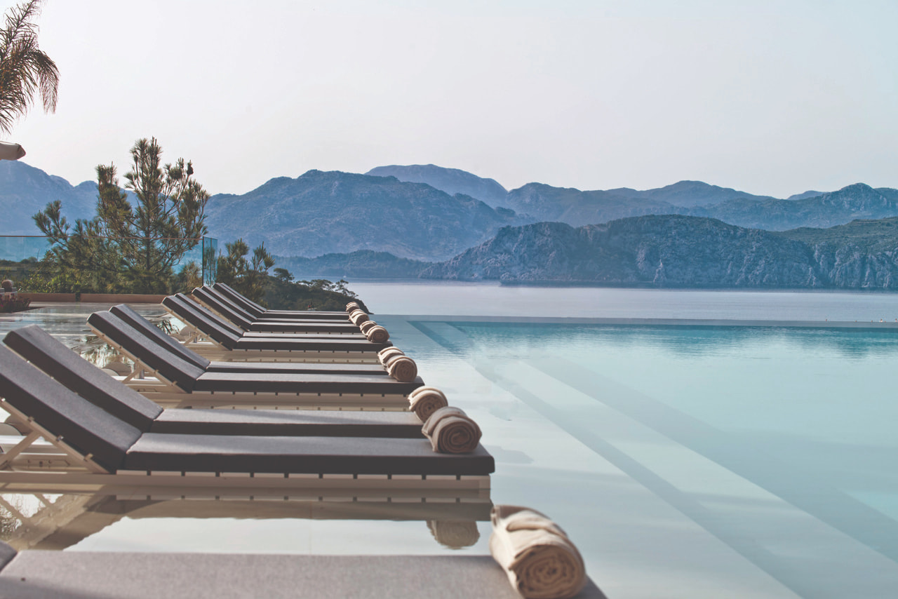 Calm outdoor pool with reclined seats, looking out onto the ocean