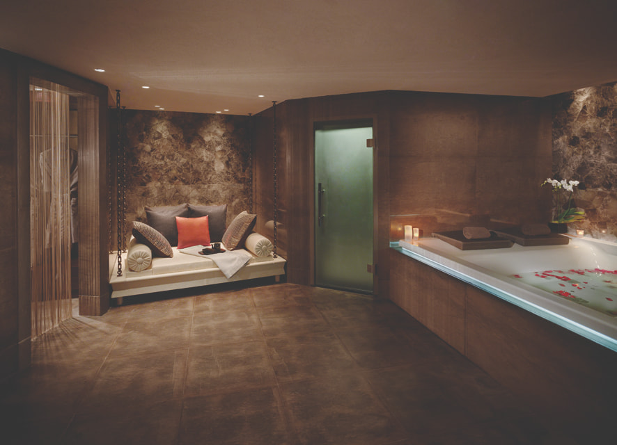 Spa room with a large bath and a pillowed seating area.