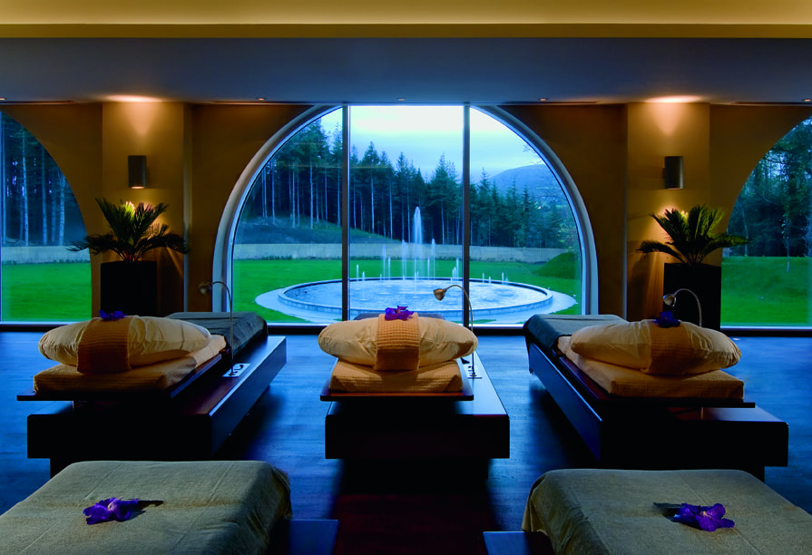 Three relaxation beds looking out through a large semicircular window onto a fountain and a forest.