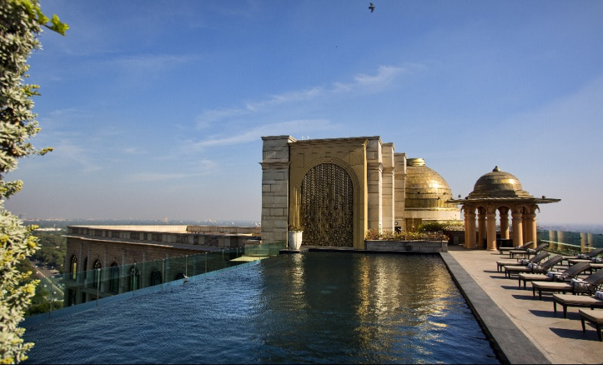 A rooftop pool with reclined beds next to a large golden roof dome.